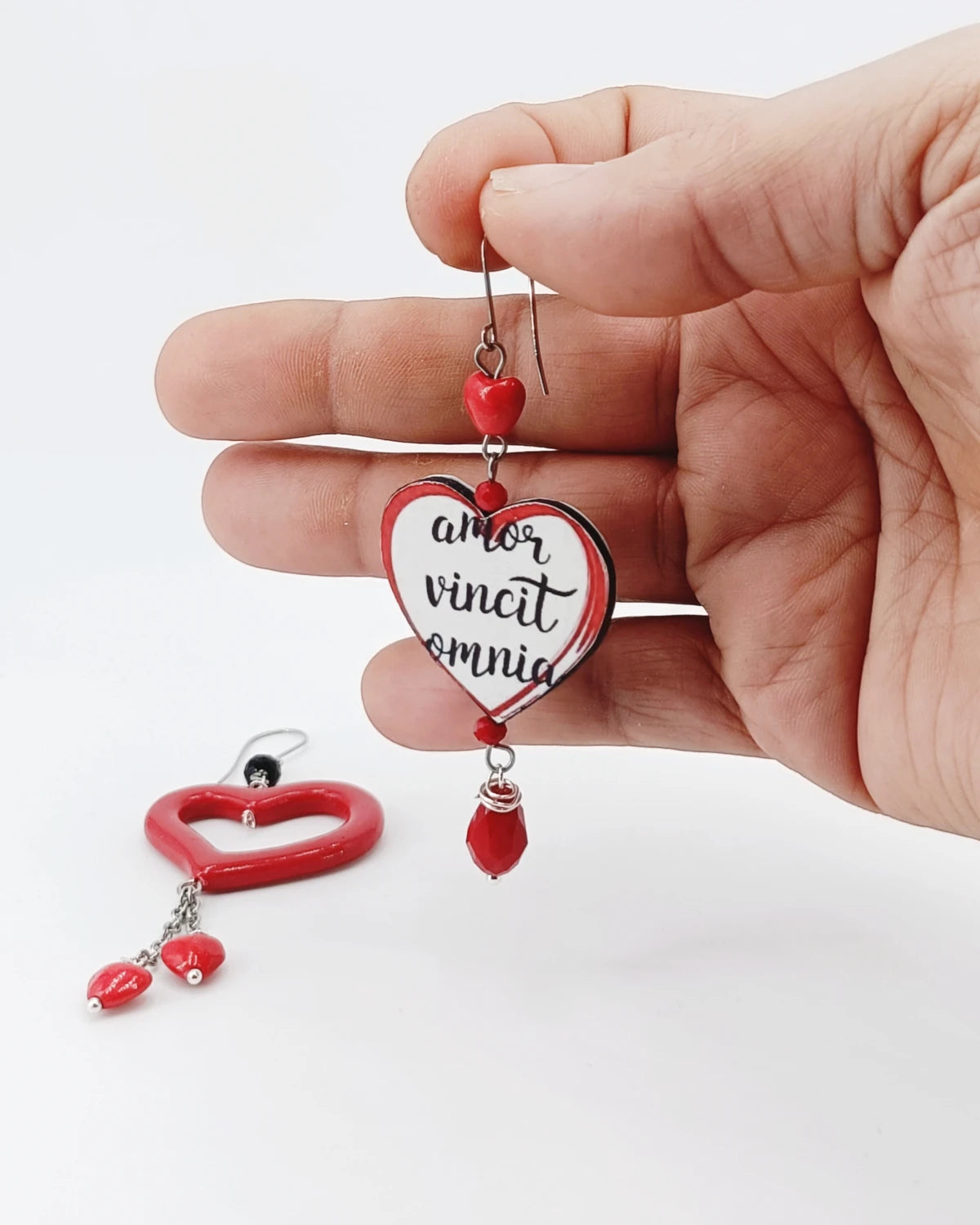 Orecchini di carta Amor vincit omia su mano
