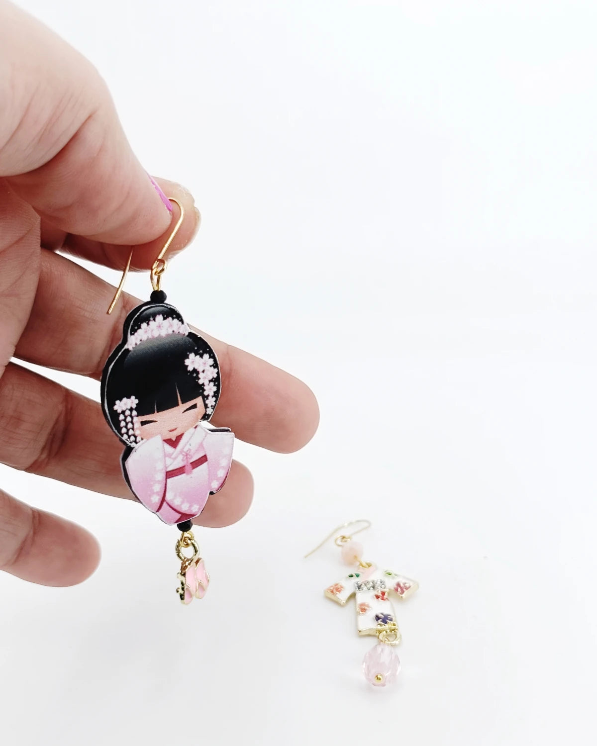 Orecchini di carta Kokeshi rosa su mano