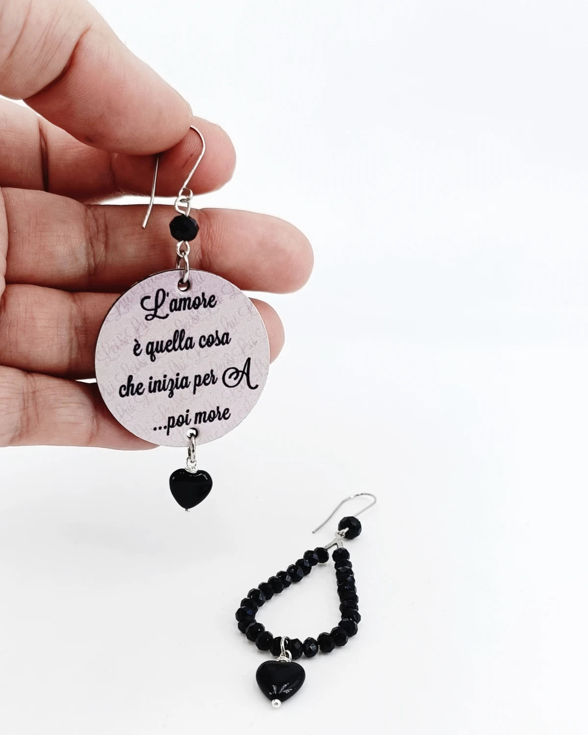Orecchini di carta Amore inizia per A poi more su mano